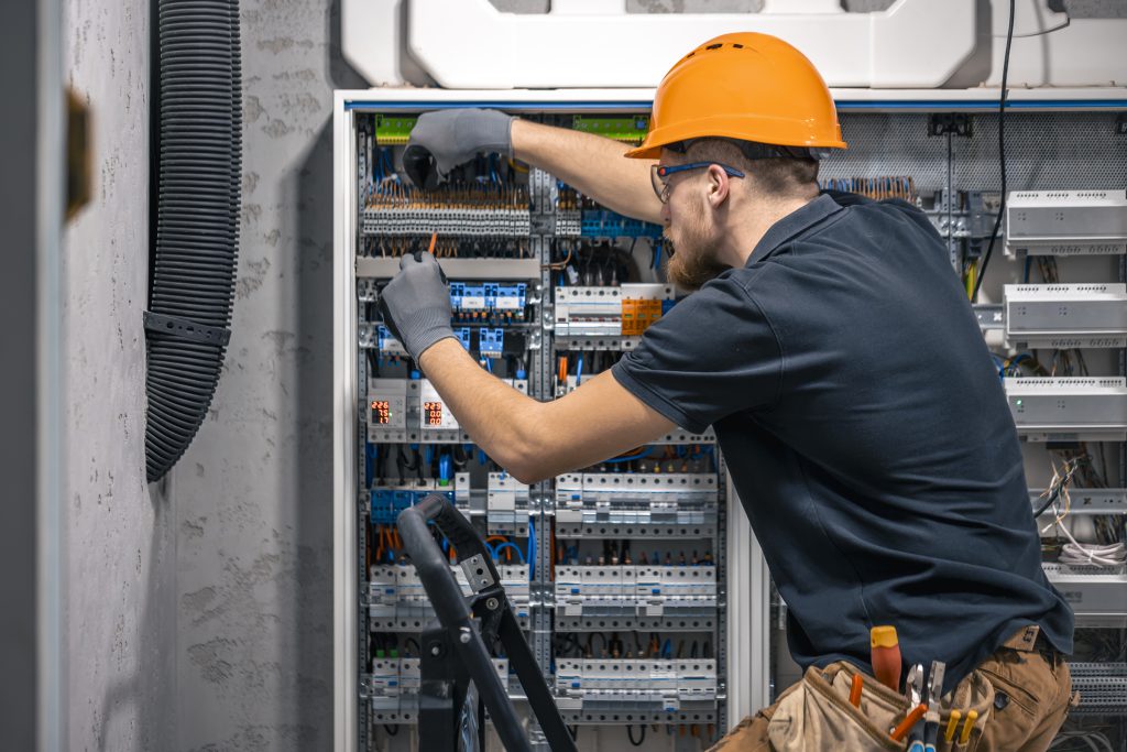 Doświadczony elektryk serwisuje rozdzielnice prądowe w budynku