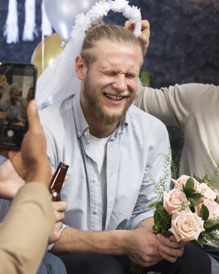 Men laughing and drinking with flowers on Kraków stag party.