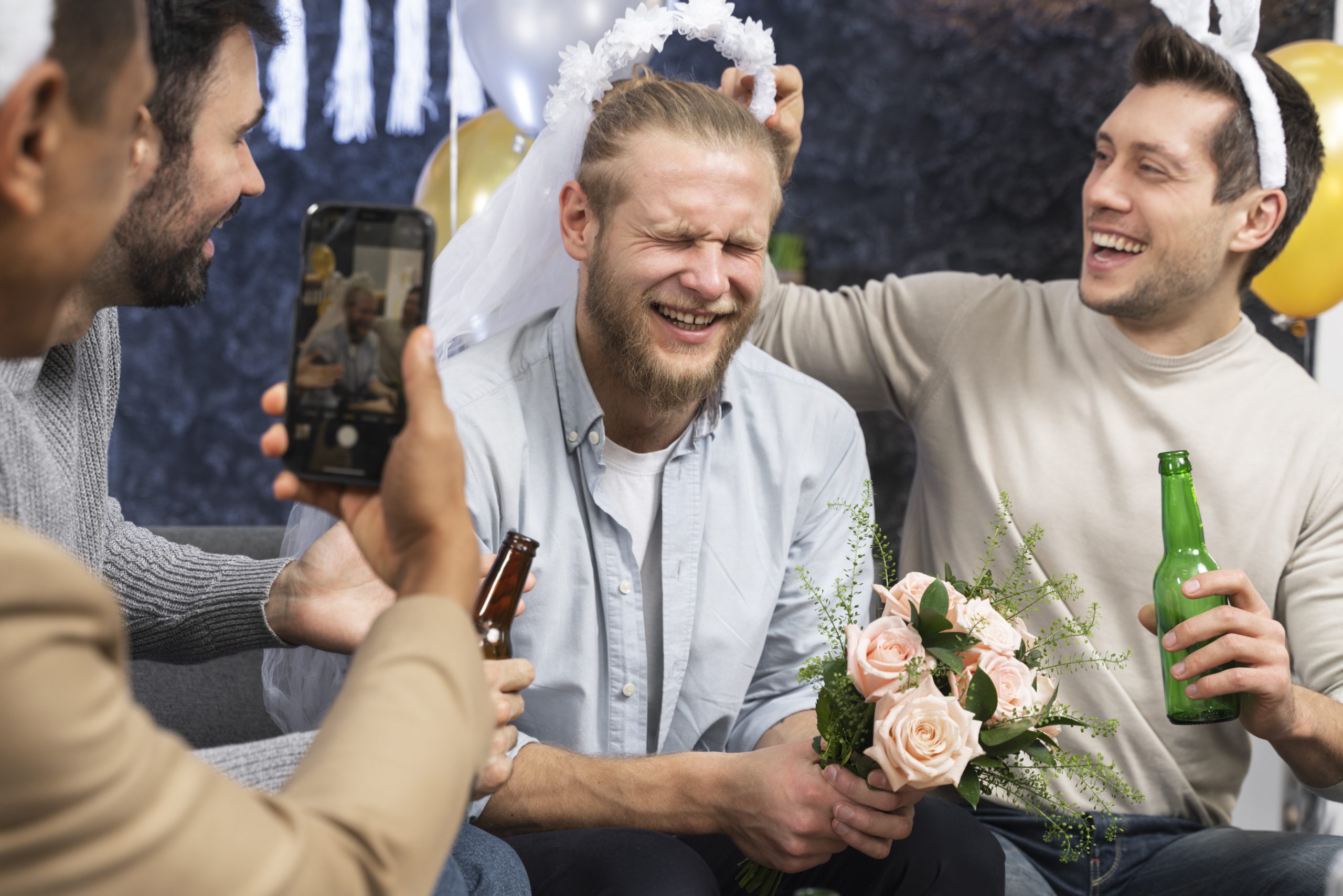 Men laughing and drinking with flowers on Kraków stag party.