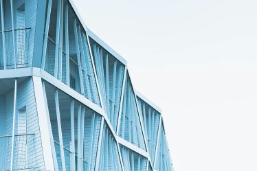 Na zdjęciu widać fragment nowoczesnego budynku o jasnoniebieskiej elewacji.