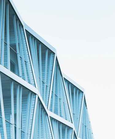 Na zdjęciu widać fragment nowoczesnego budynku o jasnoniebieskiej elewacji.