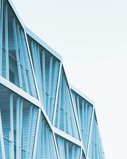 Na zdjęciu widać fragment nowoczesnego budynku o jasnoniebieskiej elewacji.