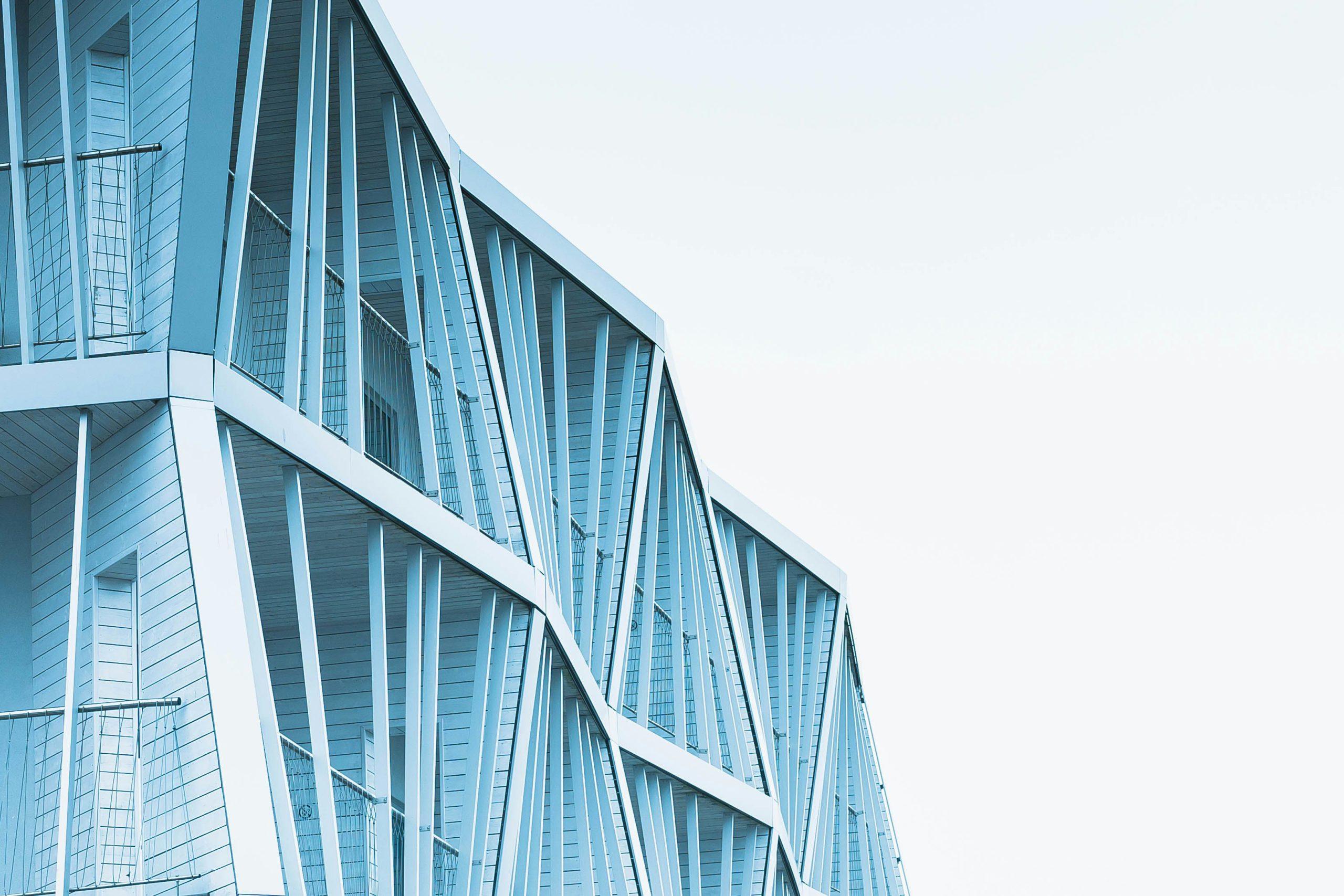 Na zdjęciu widać fragment nowoczesnego budynku o jasnoniebieskiej elewacji.