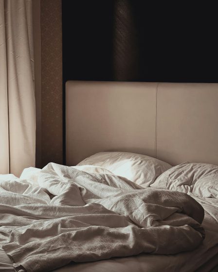 zdjęcie ukazuje niepościelone łóżko w przytulnej, stonowanej sypialni.