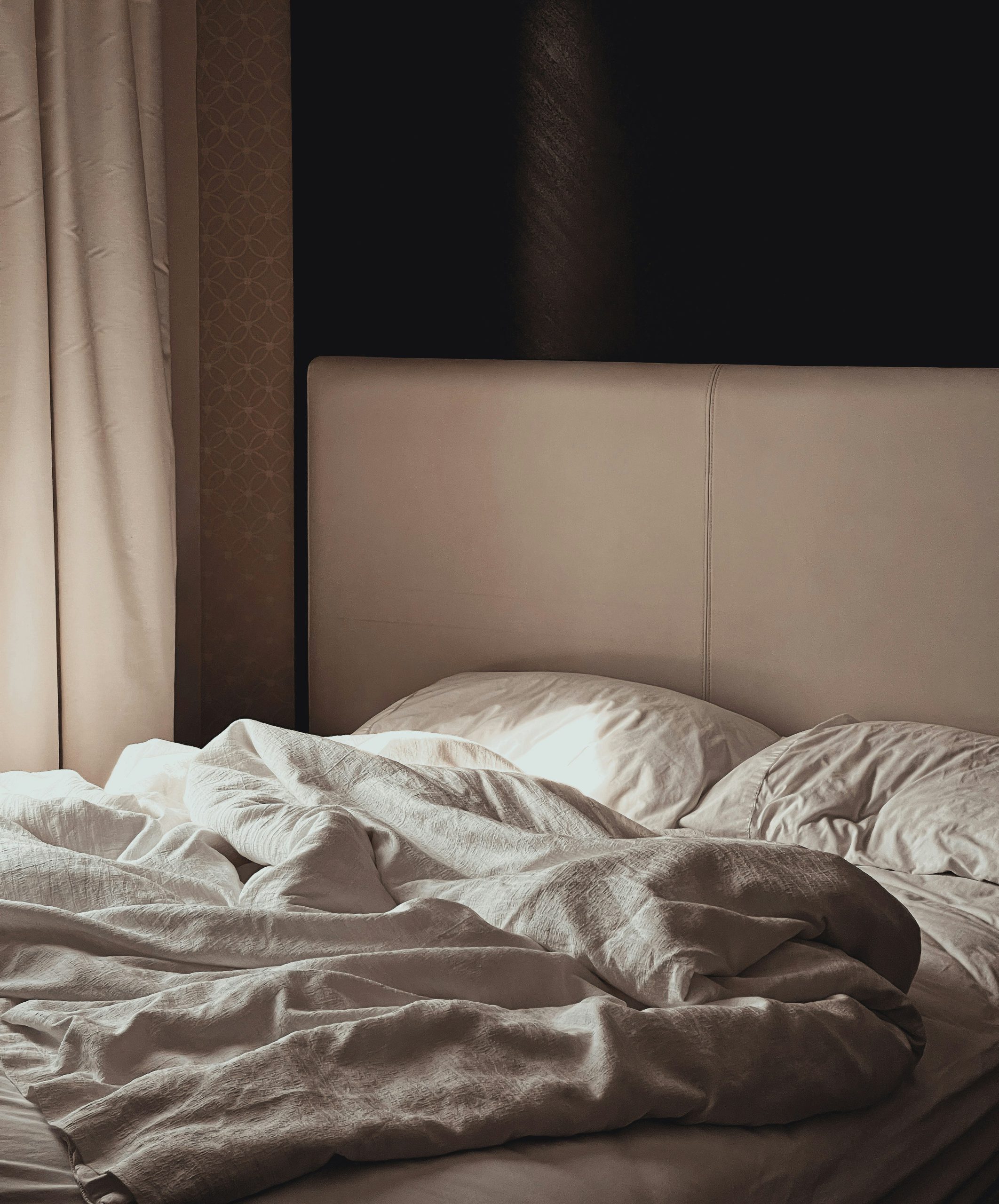 zdjęcie ukazuje niepościelone łóżko w przytulnej, stonowanej sypialni.