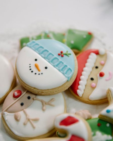 Kolorowe słodycze bożonarodzeniowe w formie okrągłych kruchych ciasteczek dekorowanych lukrem z postaciami Świętego Mikołaja i bałwana.