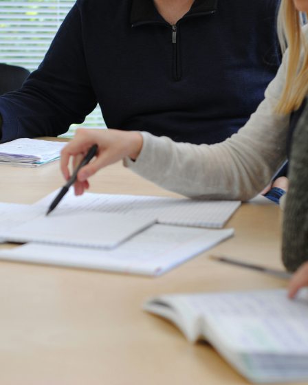 Na zdjęciu przedstawiono dwie osoby siedzące przy stole podczas wspólnej pracy nad dokumentami