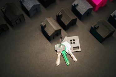 czarne modele domków i klucze leżące na czarnym tle