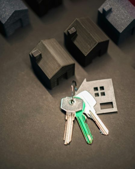 czarne modele domków i klucze leżące na czarnym tle
